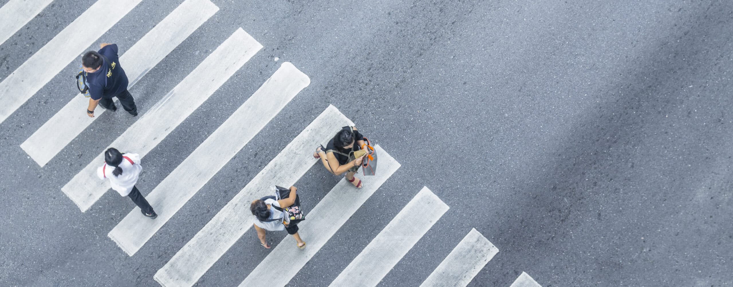 four pedestrians walk on crosswalk