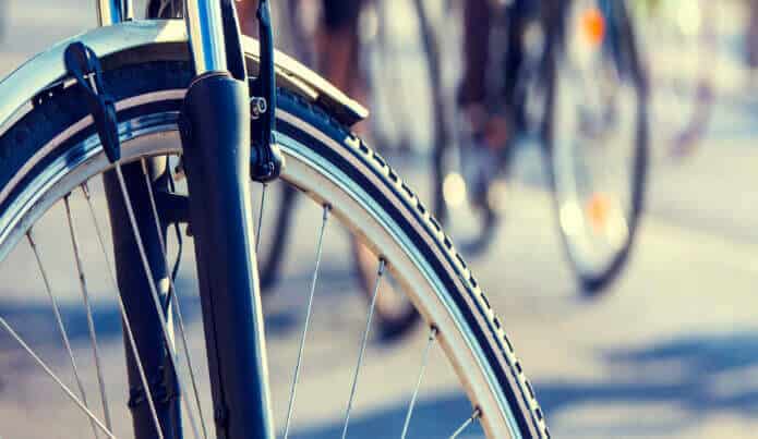 Front wheel of bicycle stopped near two moving bicycles 