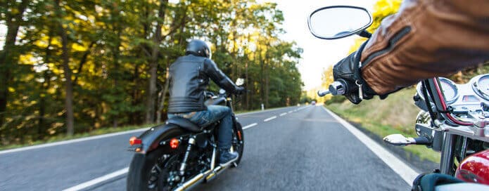 Man seat on the motorcycle on the forest road during sunrise.