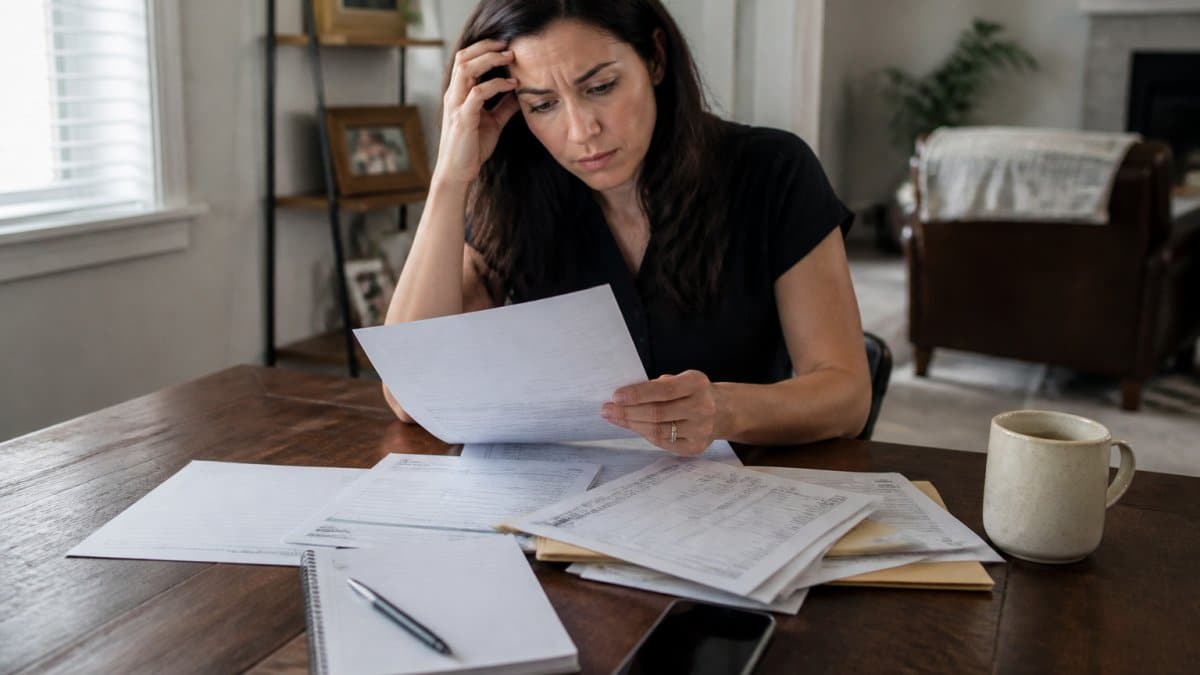 Person reviewing a denial letter at a desk with medical documents, phone, and notepad nearby, looking concerned but focused
